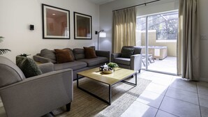 Una sala de estar moderna con un conjunto de sofás, una mesa de centro y un ventanal con cortinas.