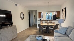 A living room with a TV, a round coffee table, a sofa, and a dining area with a table and chairs.