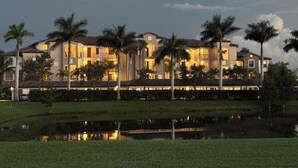 A large, multi-story hotel with a symmetrical facade, multiple balconies, and a reflective water feature in the foreground.