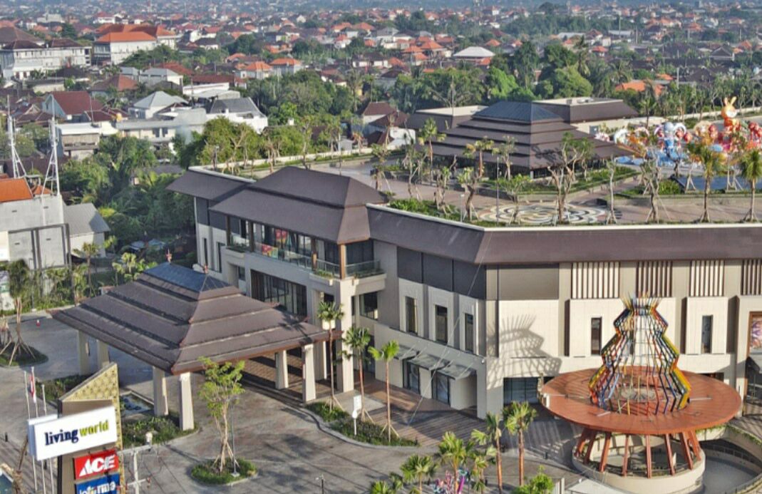 A modern building with a central atrium, surrounded by residential areas and greenery.