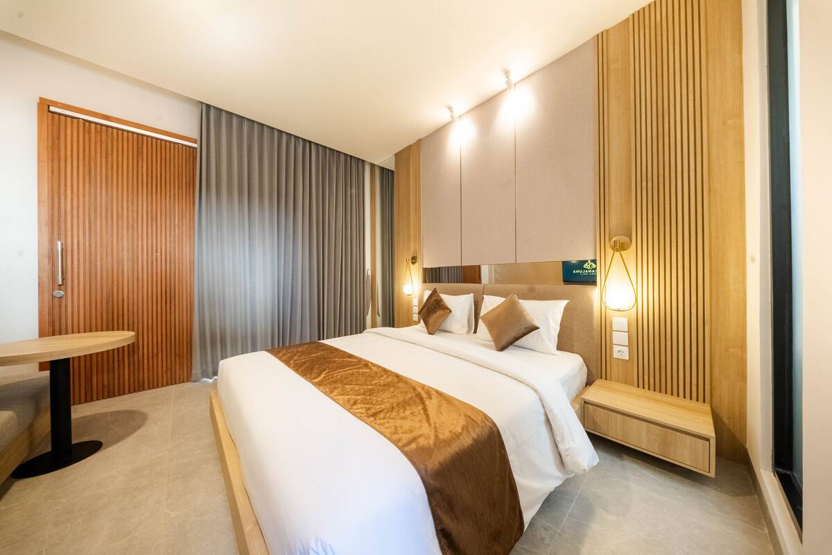 Een moderne hotelkamer met een groot bed, een houten bureau en een ingebouwde bank.