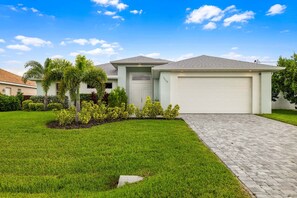 A single-story house with a garage, surrounded by a well-maintained lawn and small shrubs.