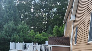 Um imóvel residencial com um caminho de concreto que leva a um deck de madeira branca com guarda-corpo.