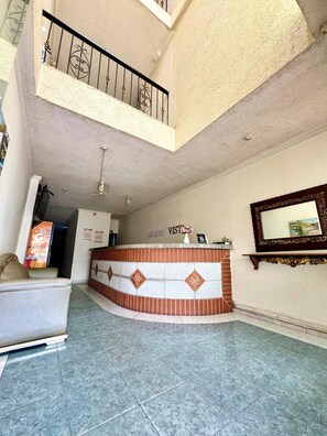 A reception area with a reception desk, a sofa, a staircase, and a wall-mounted mirror. - Hotel Buenavista Valledupar (Valledupar)
