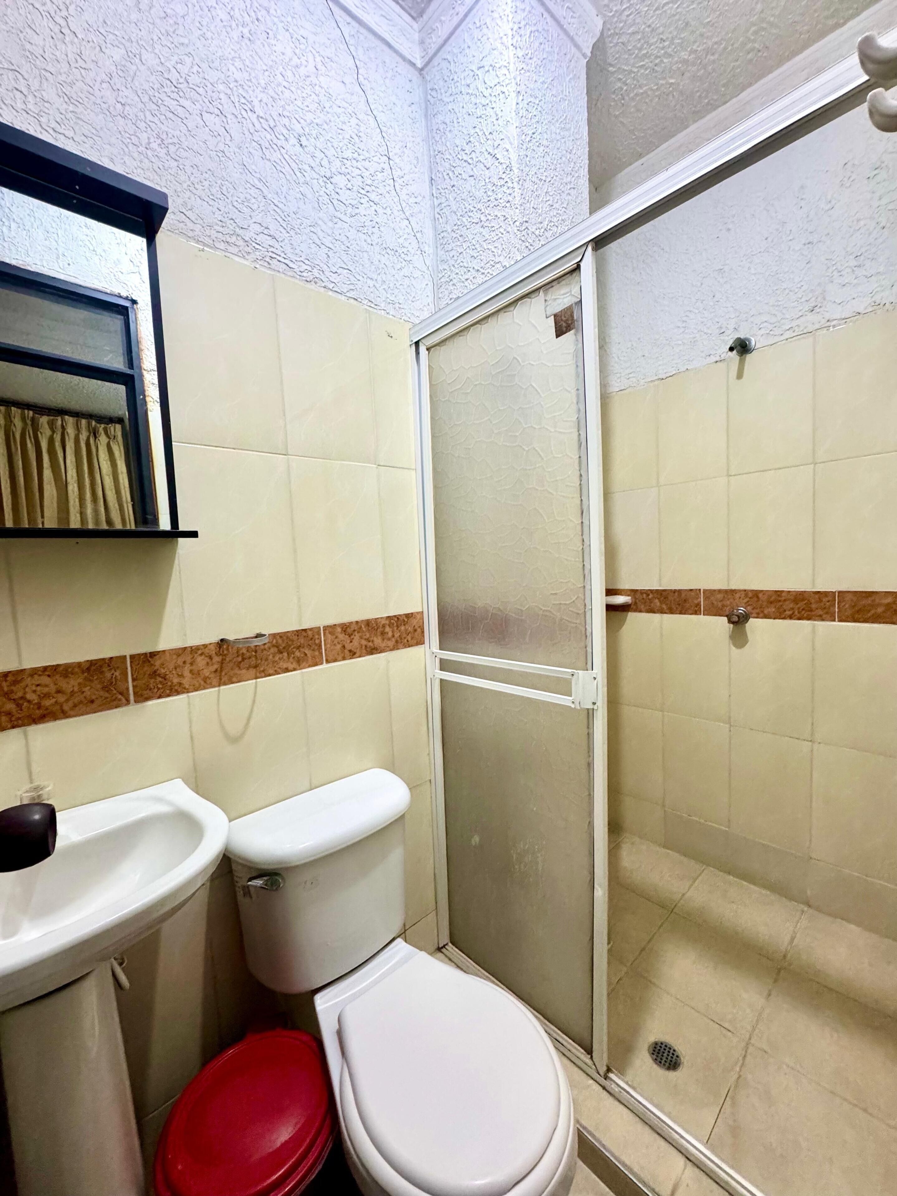 A bathroom with a toilet, sink, and shower area.