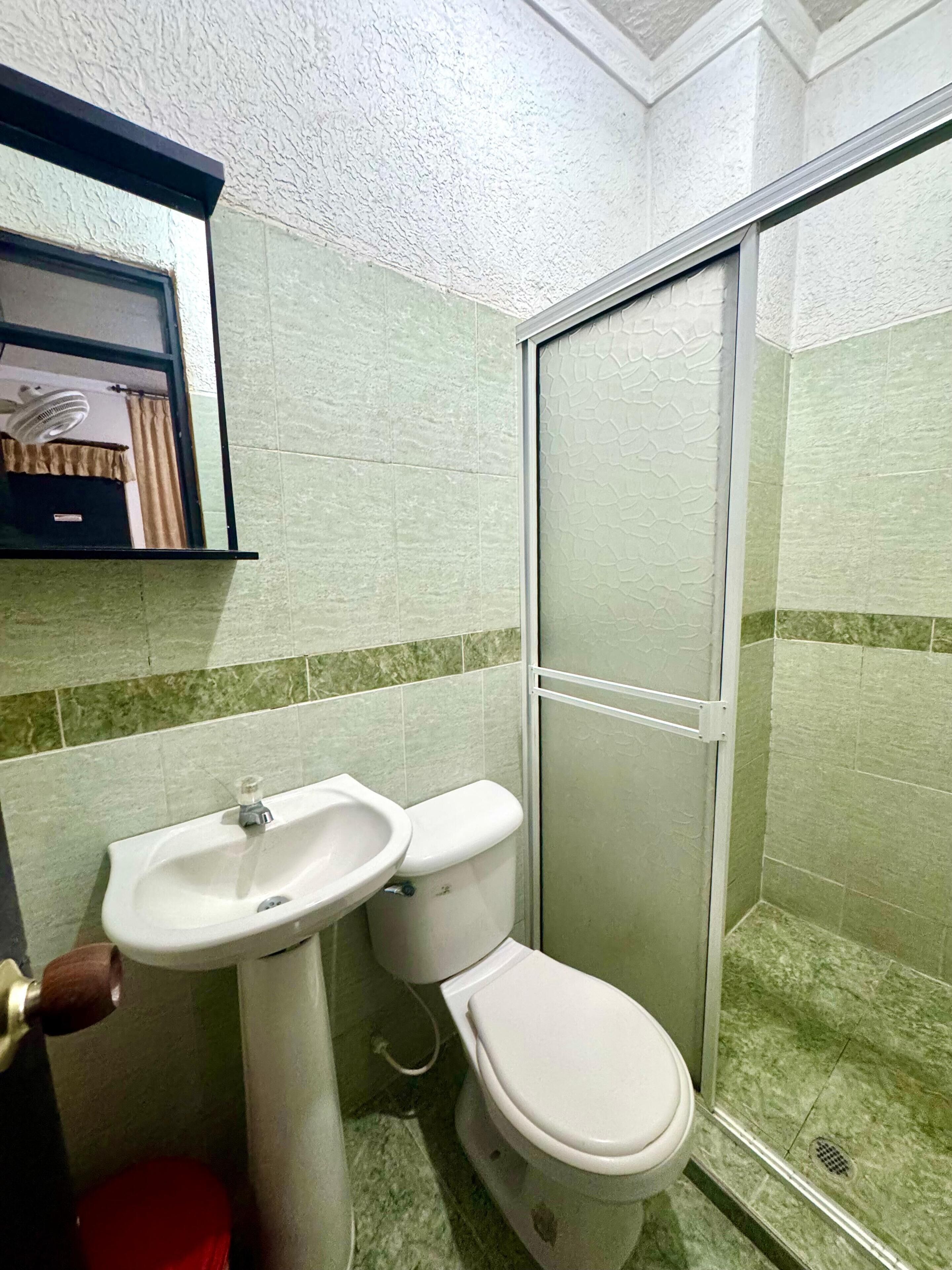 Un baño con lavabo, inodoro y cabina de ducha de vidrio.