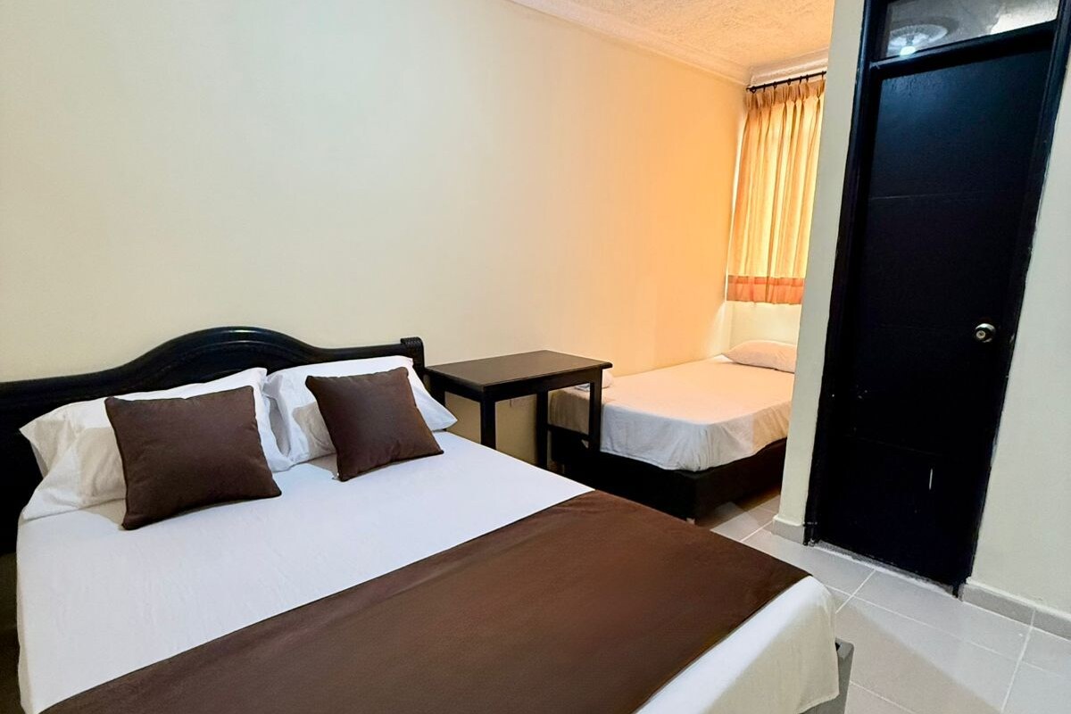Una habitación de hotel con cama, mesita de noche y una puerta.