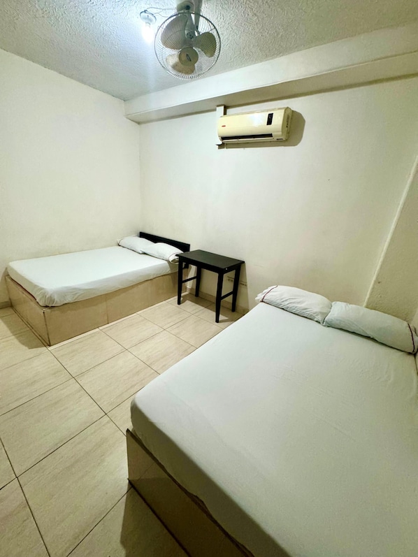 A room with two single beds, a small table, a ceiling fan, and an air conditioning unit. - Hotel Buenavista Valledupar (Valledupar)
