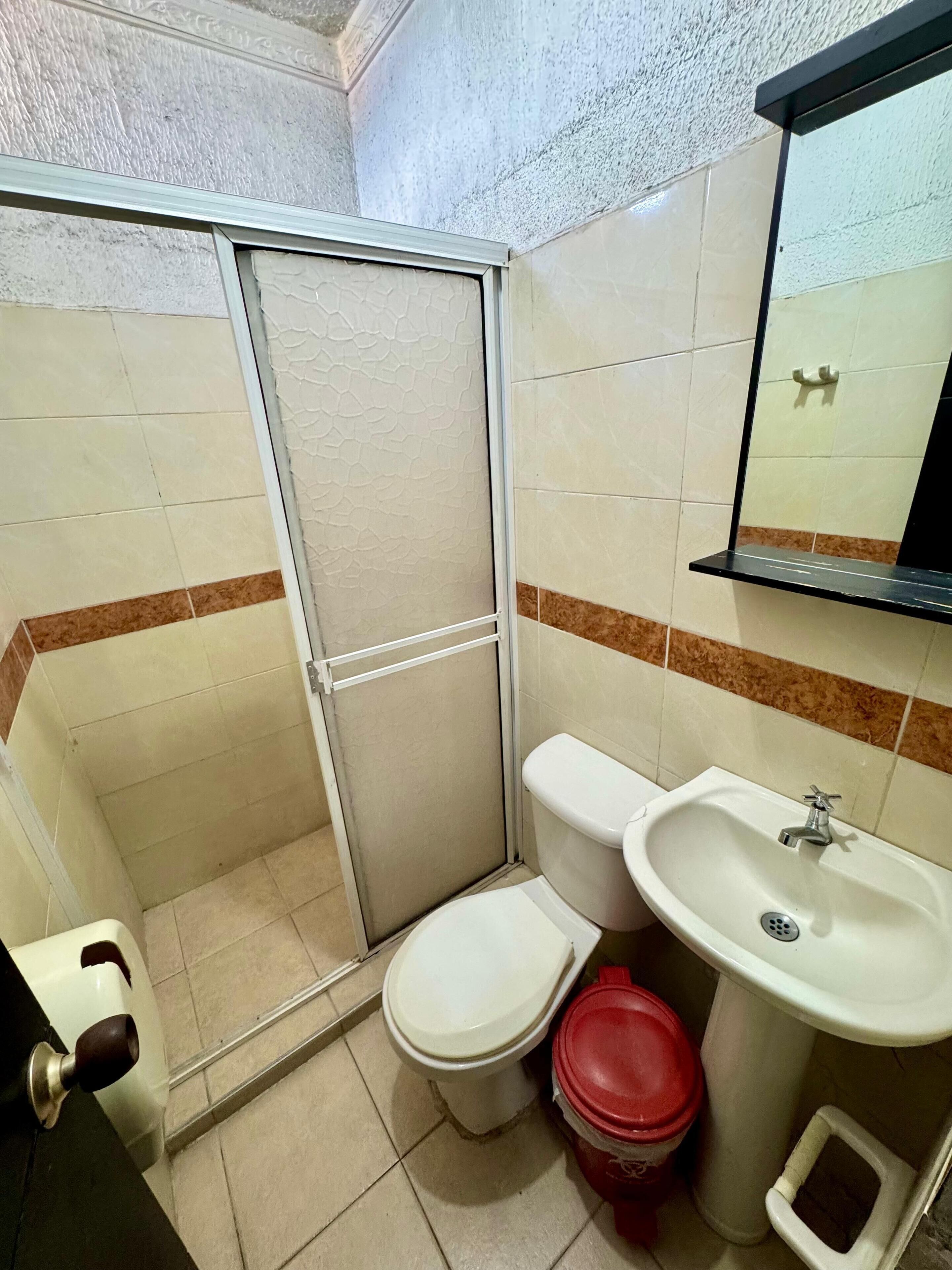 A small bathroom with a toilet, sink, and shower.