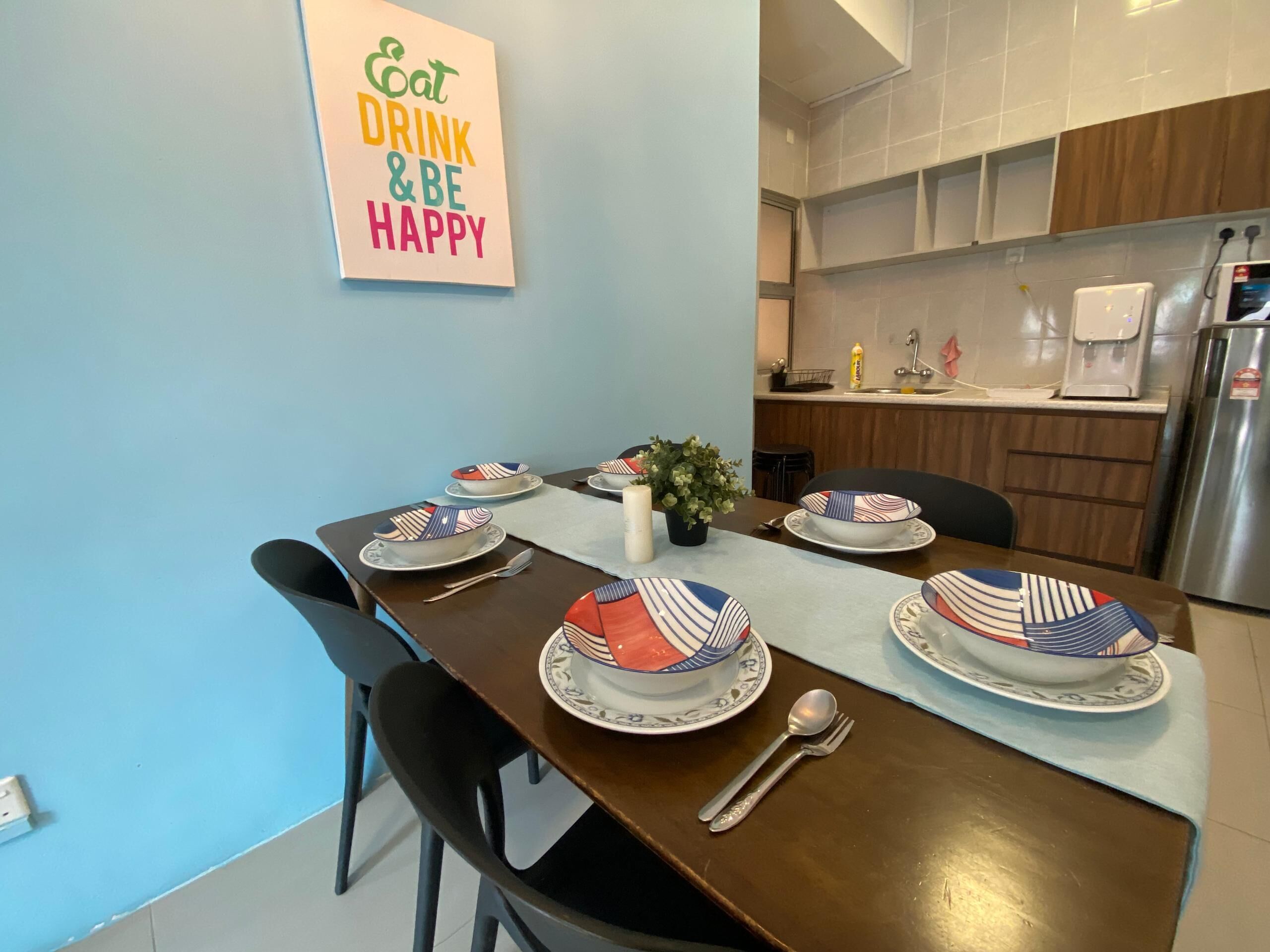 Une table à manger dressée avec des assiettes, des couverts et un chandelier en guise de décoration centrale.