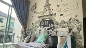 A bedroom with a bed, a small table, and a wall mural of Parisian landmarks. - Cameron Golden Hill Near Night Market CH1 (Brinchang)
