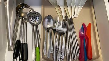 A drawer containing various kitchen utensils including spoons, forks, and a grater.
