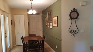 Un comedor con una mesa y sillas de madera, una araña y cuadros en la pared.