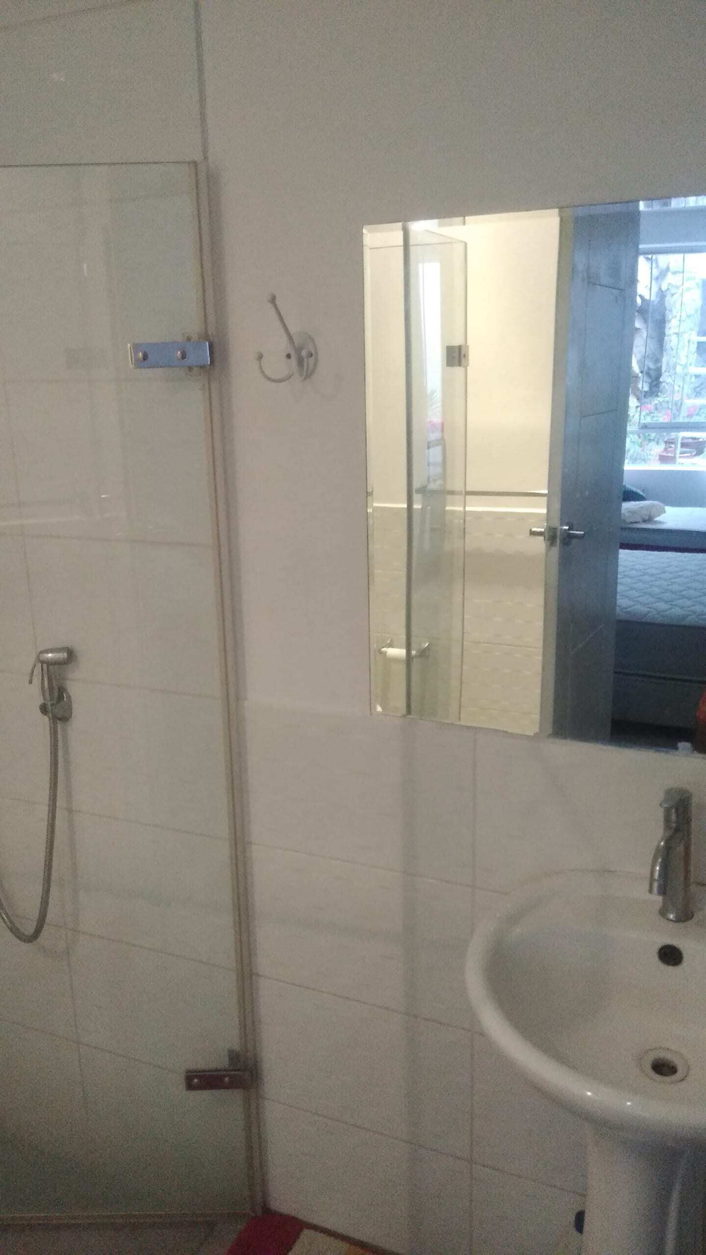 Et badeværelse med bruser, vask og spejl.