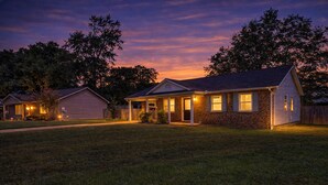 Une maison d’habitation avec une pelouse bien entretenue, un porche à l’avant et un garage.