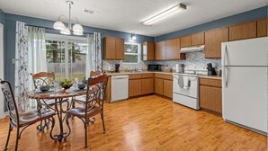 Une cuisine moderne avec des meubles en bois, un réfrigérateur blanc et un coin repas comprenant une table et des chaises.