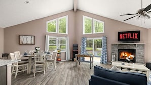 A spacious living room with a fireplace, a foosball table, and a large window overlooking a deck.