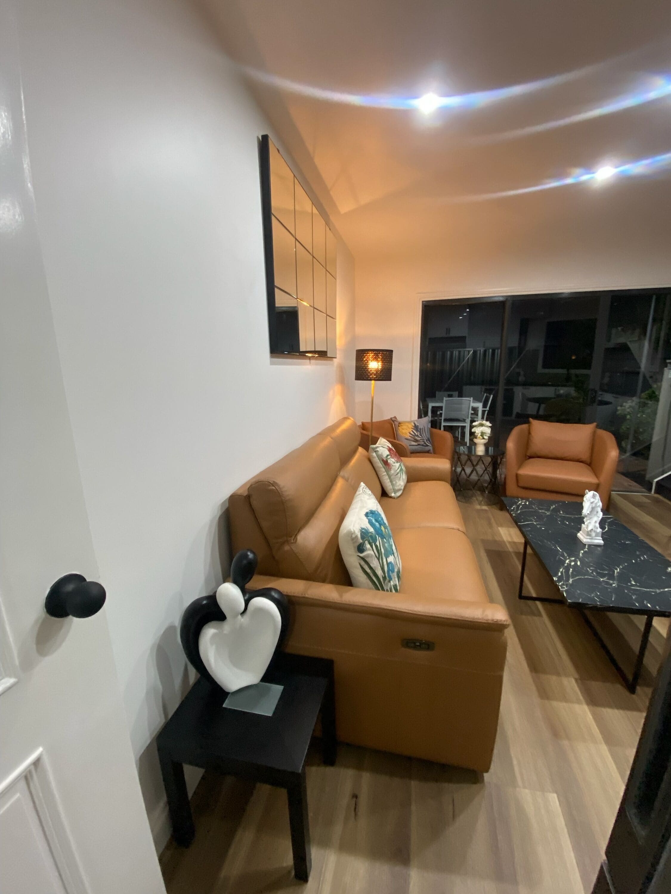 Un salon moderne avec un canapé marron, une table basse noire et une petite table noire ornée d’un objet décoratif.