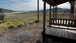 A wooden porch with a view of a lake and distant mountains. - Nice quaint cabin in Panguitch Lake UT with a great view! (Panguitch)