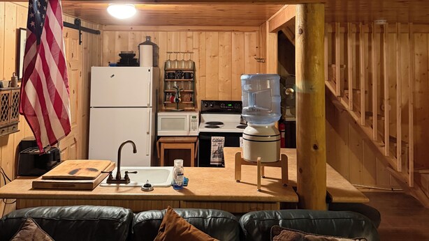 En stuga med ett kök, en matplats, en vattenautomat och en flagga.