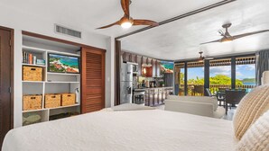 A modern hotel room with a large bed, a kitchenette, a dining area, and a balcony with a scenic view.