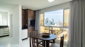 A modern living room with a dining area, large windows with city views, and a kitchen area. - CII - Apartments 900m From the Beach in Porto Belo (Porto Belo)