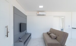 Un salon moderne avec un téléviseur à écran plat, un canapé et un appareil de climatisation fixé au mur.