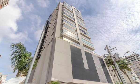 A high-rise building with multiple floors, large windows, and a modern architectural design. - New Apartment 150m From Pereque Beach Cle1202 (Porto Belo)