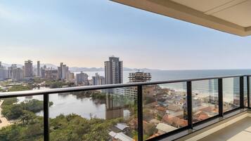 A balcony with a view of a cityscape, a body of water, and distant mountains.