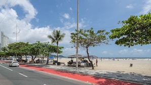 Eine Straßenansicht am Strand mit einer roten Radspur, Palmen und einem Strand im Hintergrund.