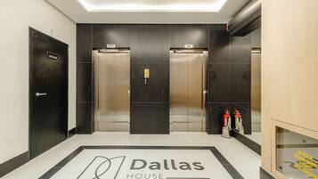 Vestíbulo de hotel Dallas House Seozone con dos ascensores, un extintor y una recepción.