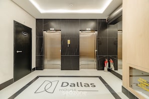 Hotellobbyn på Dallas House Seozone har två hissar, en brandsläckare och en receptionsdisk.