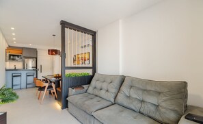 A modern living room with a grey sofa, a dining area with wooden chairs, and a kitchen with grey cabinets and a black countertop. - Apt Sea View 500m Beach Itapema Dsh1702 (Itapema)