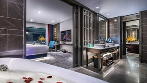 Een moderne hotelkamer met een groot bed, een badkamer met bad en uitzicht op de stad.