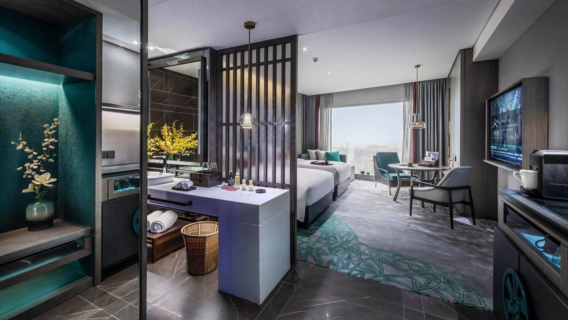 Una moderna camera d'albergo con un letto grande, un'area salotto con un tavolo e sedie, una TV e un bagno con un lavabo e una vasca.