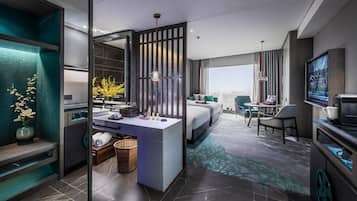 Una moderna camera d'albergo con un letto grande, un'area salotto con un tavolo e sedie, una TV e un bagno con un lavabo e una vasca.