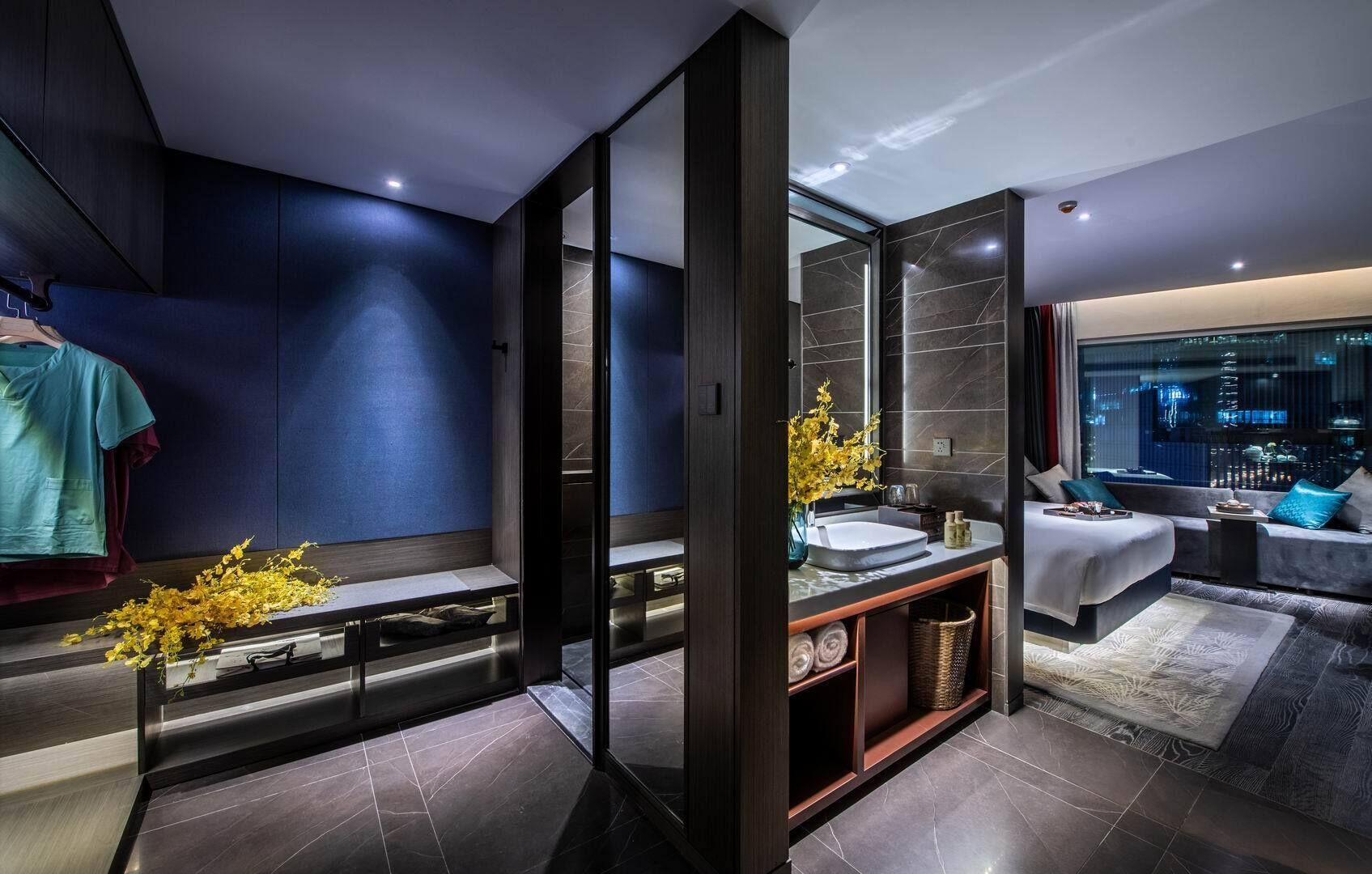 A modern bathroom with a vanity, a large mirror, and a seating area with a view of the city.