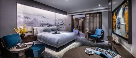 Una habitación de hotel moderna con una cama grande, un área de descanso con una mesa y un televisor.