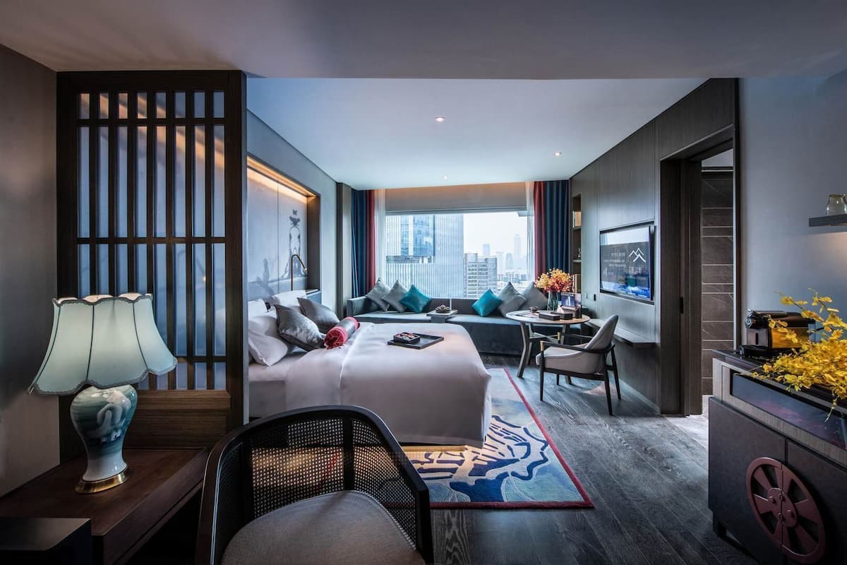 Una habitación de hotel moderna con cama, zona de estar y escritorio.