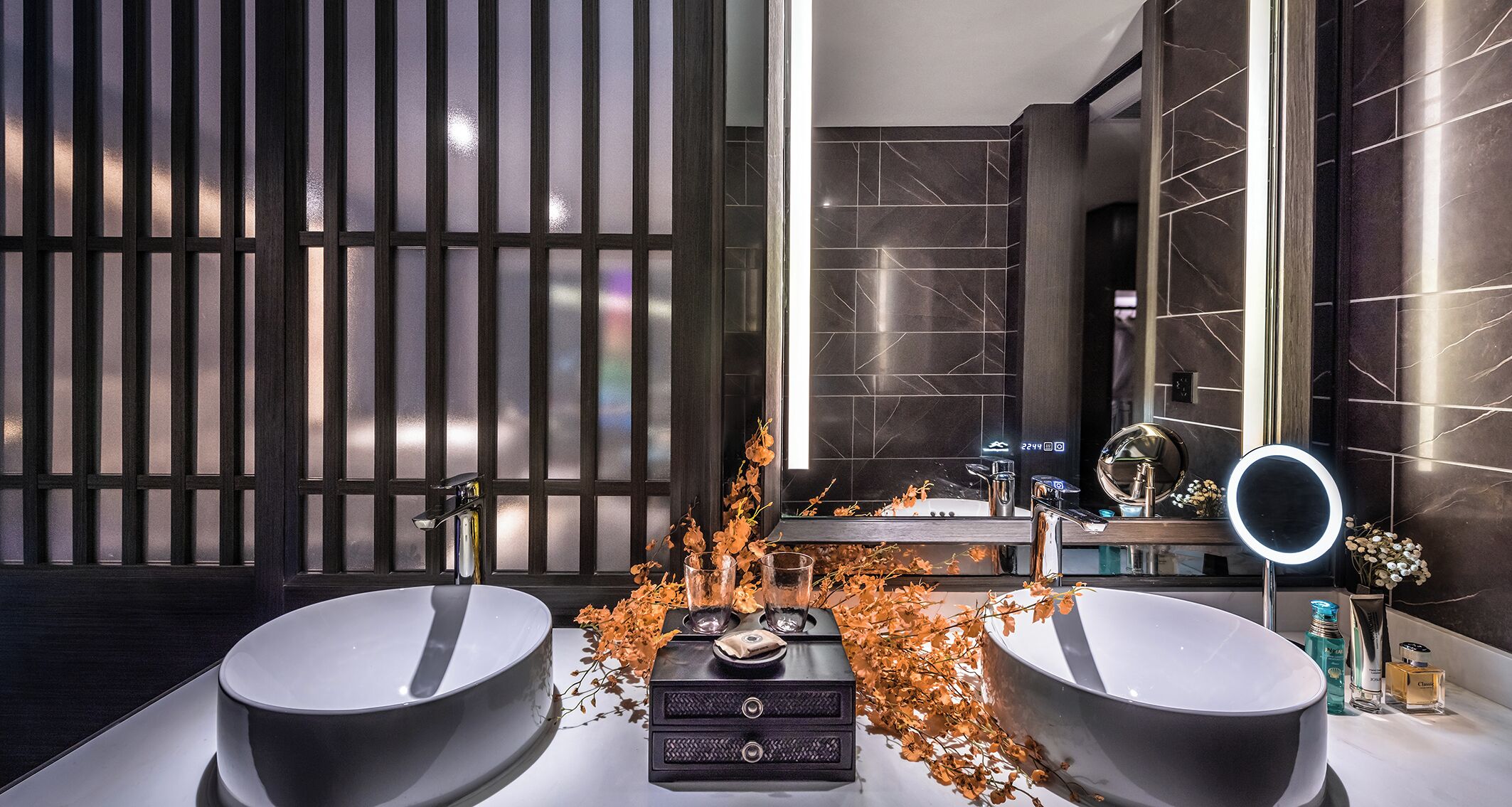 A modern bathroom with two sinks, a vanity with a mirror, and decorative elements like autumn leaves.