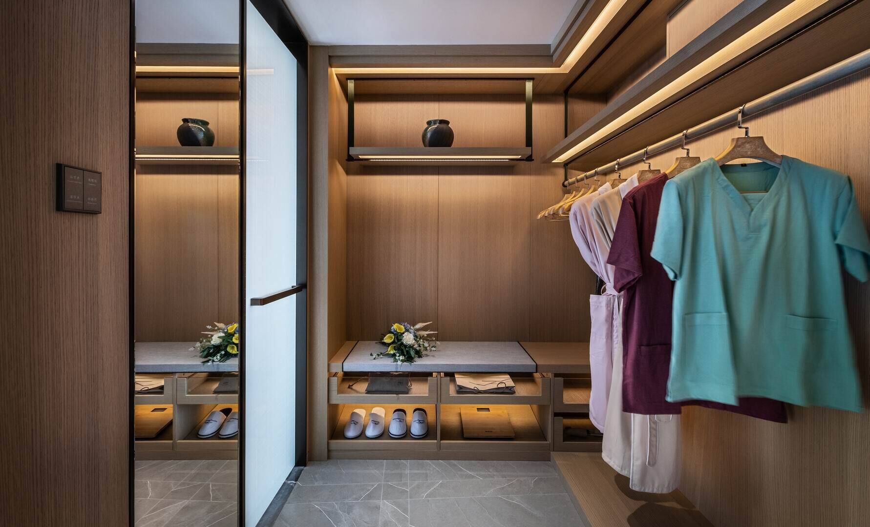 Un vestidor moderno con paneles de madera, estantes empotrados y un zapatero.