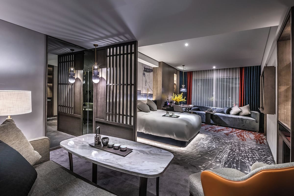 Una habitación de hotel moderna con sofá, una mesa de comedor, una cama y una zona de estar.