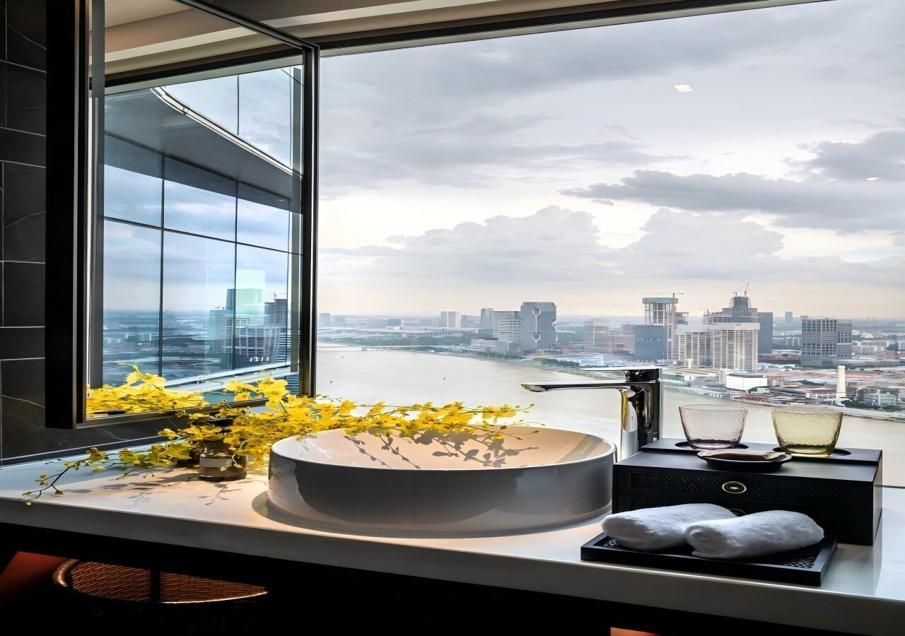 A modern bathroom with a large window, a round sink, and a view of a cityscape.