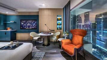 A modern hotel room with a city view, a dining area, and a large TV.