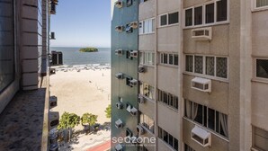 Un immeuble de grande hauteur doté de plusieurs unités de climatisation, offrant une vue sur la plage et sur une île située au loin.