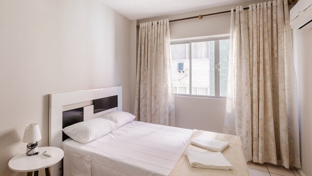 Une chambre à coucher avec un lit, une table de chevet et une fenêtre avec des rideaux.