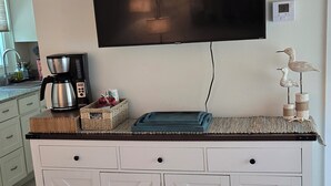 Cuina amb un televisió de pantalla plana penjada sobre un armari blanc amb calaixos.