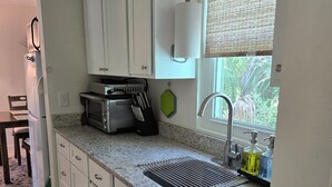 Cuina amb armaris blancs, microones, torradora i rentapelats amb dosificadors de sabó.