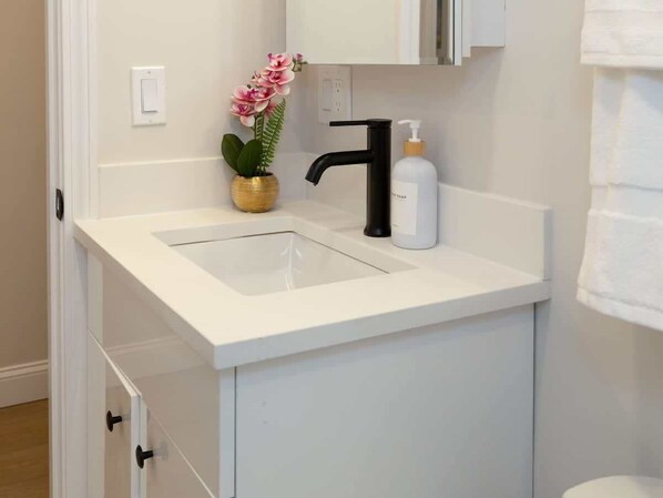 A bathroom with a white sink, black faucet, and a soap dispenser.