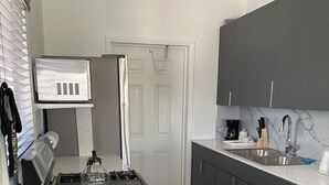 A modern kitchen with a gas stove, a microwave, and a sink. - Brand new 2-bedroom cottage, Harts Exuma across the street from the beach (Exuma)